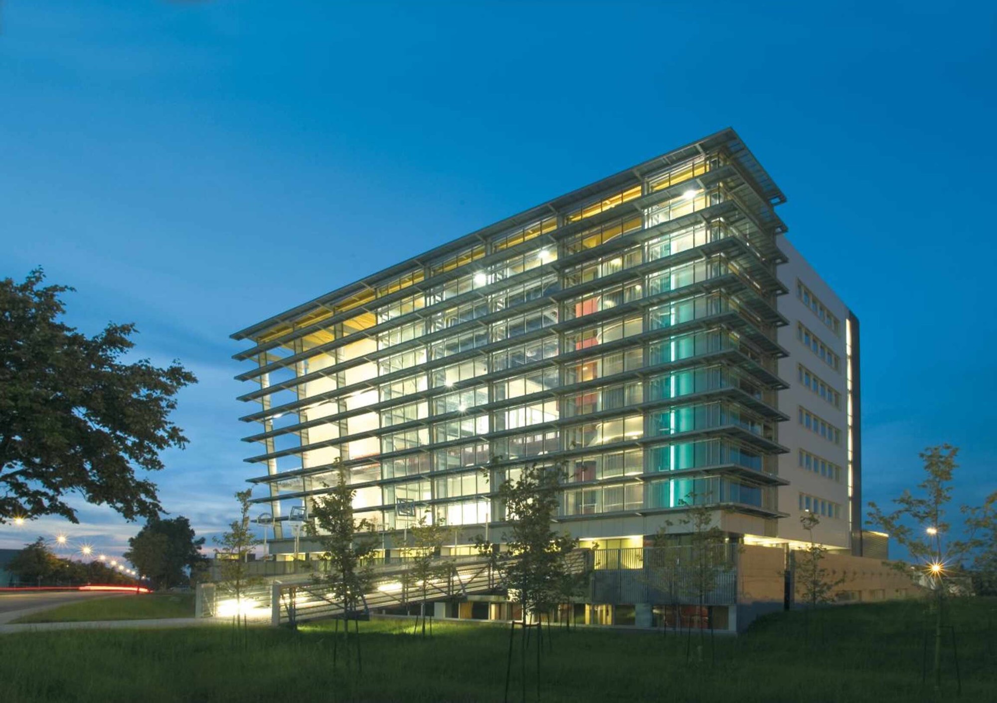 The École nationale de cirque building in Montréal at dusk: a glass facade lit from inside, with horizontal sunshades on every floor.