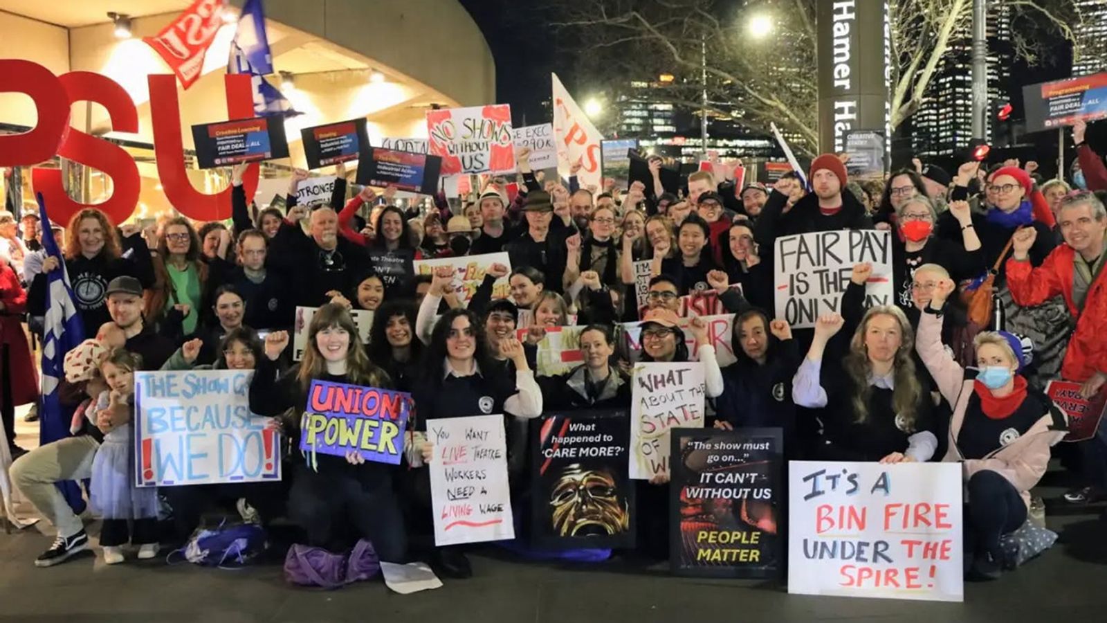 Arts Centre Melbourne workers on strike outside Hamer Hall at night, holding placards