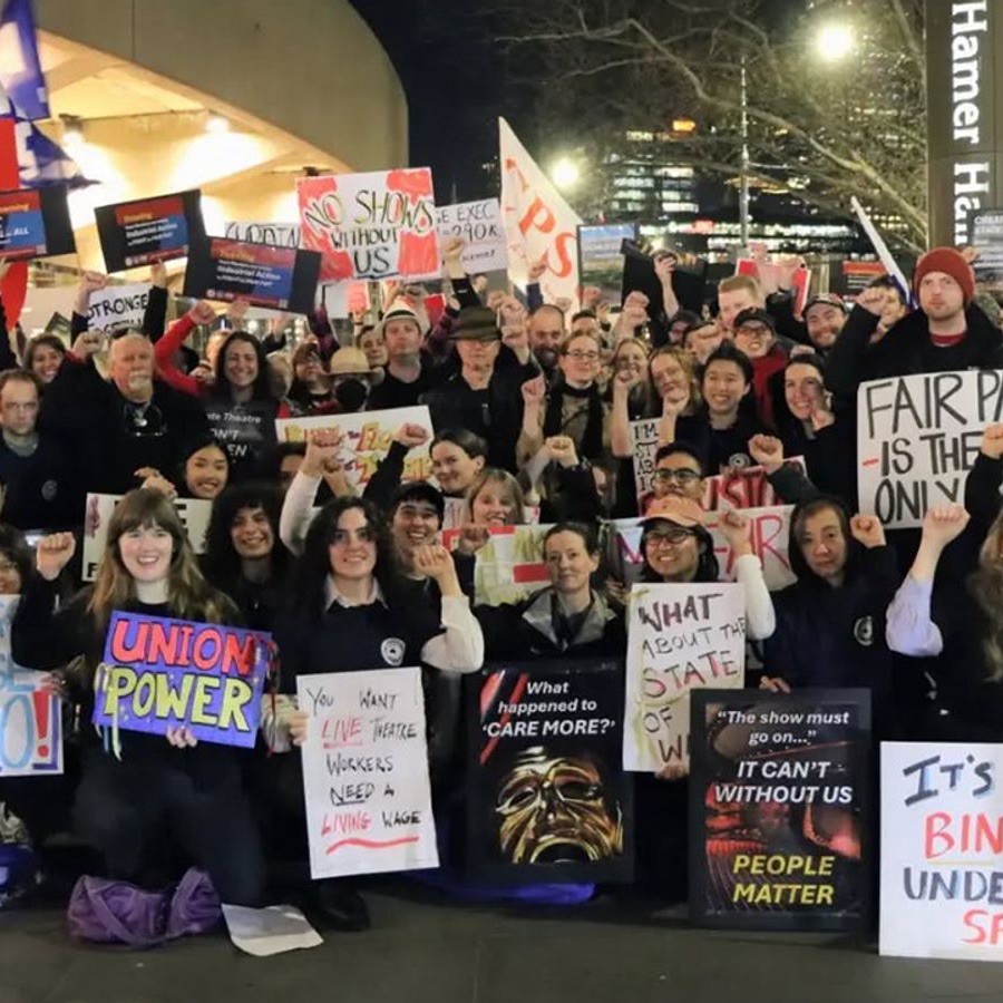 Arts Centre Melbourne workers on strike outside Hamer Hall at night, holding placards