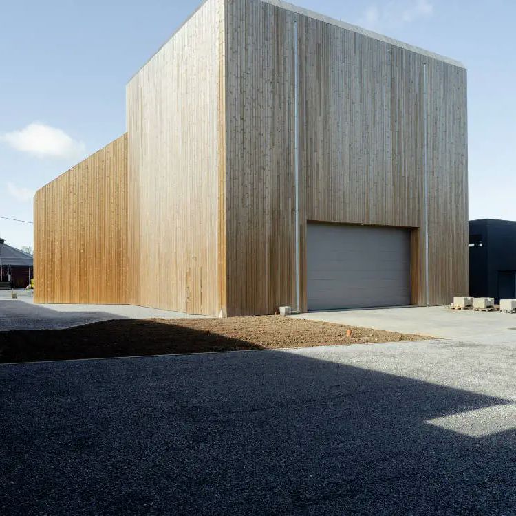 An architect's render of the future Latitude 50 hall in Marchin, a tall timber-clad building with the Latitude 50 name in red across its upper wall, beside a dark block marked Ecole Cirque Marchin